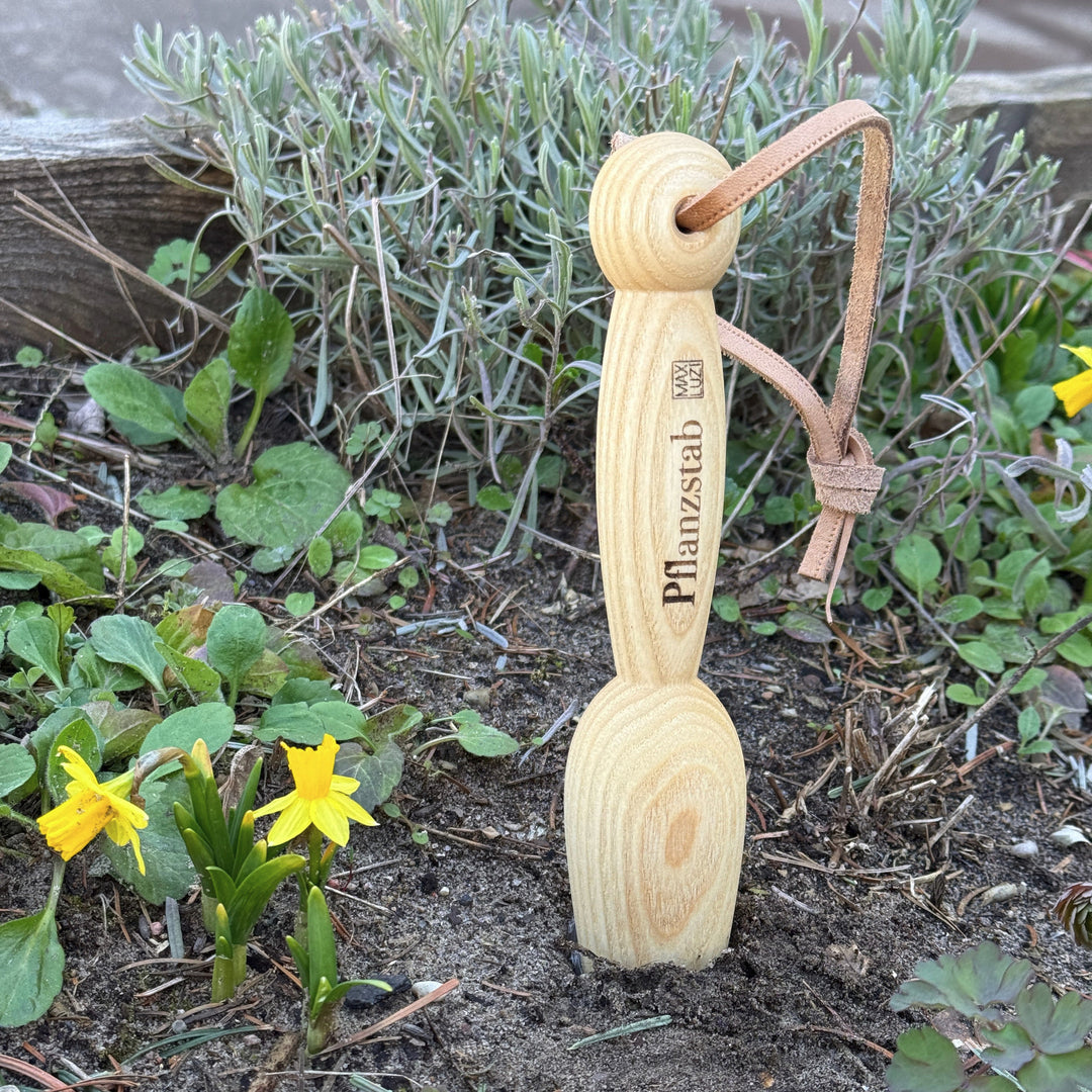 ein pflanzholz aus eschenholz gedrechselt in einem blumenbeet