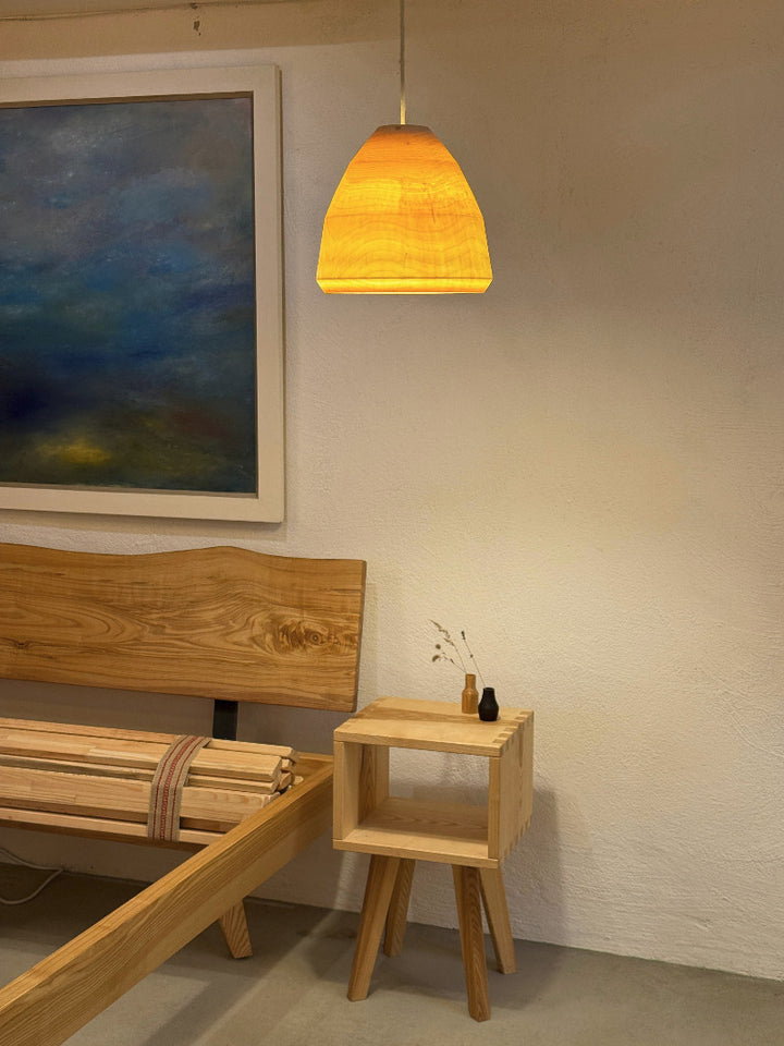 gedrechsetle Holzlampe im Innenraum mit Bett und Bild und Nachttisch