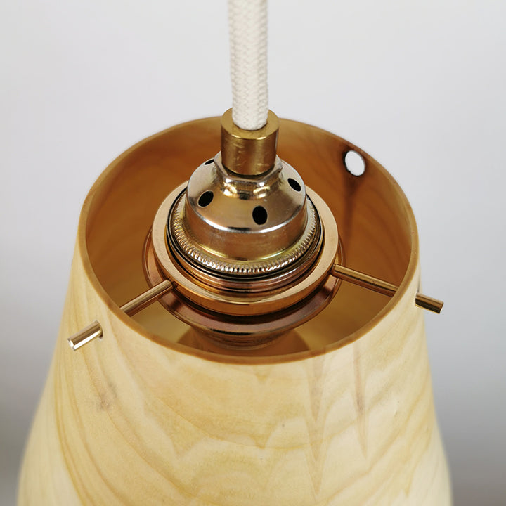 Detailfoto einer gedrrechselten Holzlampe mit Messingfassung und Textilkabel.