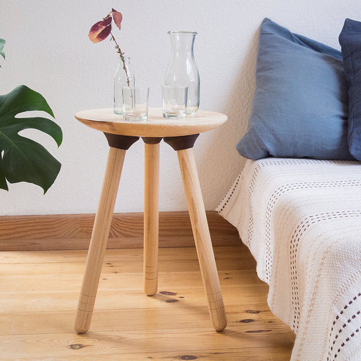 Gedrechselter Hocker aus Eschenholz mit drei Beinen mit Sofa und Kissen, Gläsern und einer Vase, und einer Pflanze
